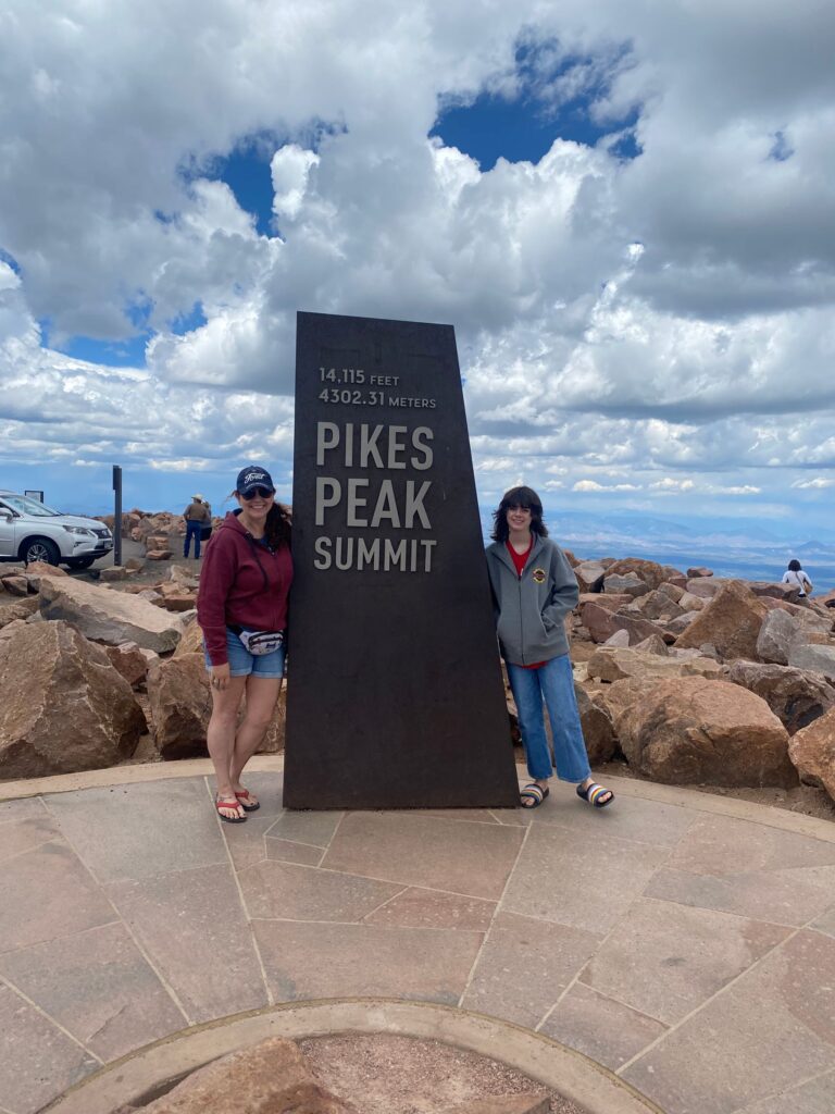 road trip pikes peak summit 2 girls at summit sign